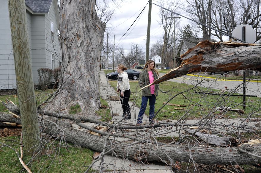 Megan Kenison and Danielle Baartos look around at the damage outside the house they live in after a storm, Monday, April 14, 2014, in Lake Orion, Mich. A wave of severe thunderstorms has blown across the southern half of Michigan, knocking out power to at least 174,000 homes and businesses and shutting down parts of two interstate highways because of fallen power lines. (AP Photo/Detroit News, Charles V. Tines) DETROIT FREE PRESS OUT; HUFFINGTON POST OUT