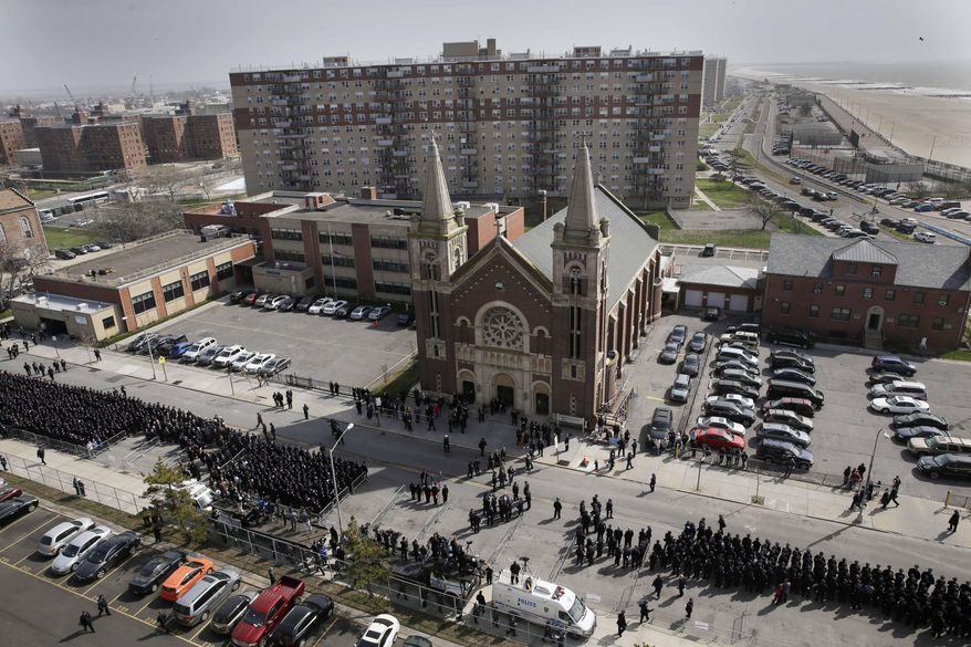 Thousands of police officers gather in front of the Saint Rose of Lima Church for the funeral of Officer Dennis Guerra in the Rockaway Beach section of Queens in New York, Monday, April 14, 2014. Guerra died Wednesday after being overcome by smoke from a Brooklyn mattress fire. He was the first NYPD officer killed in the line of duty since 2011. His partner remains in critical but stable condition. (AP Photo/Seth Wenig)