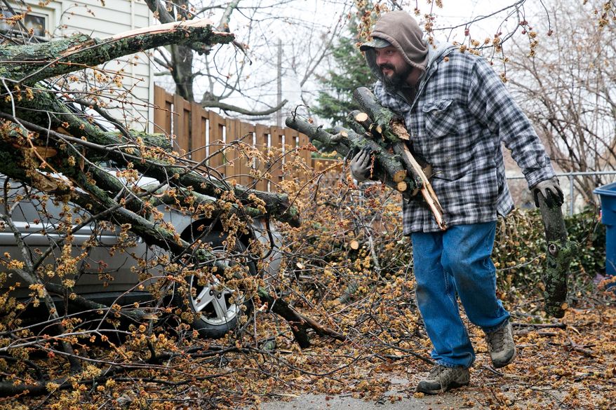 Mike Bourdon helps remove branches from his friend's driveway on Sunday, April 13, 2014. The storm hit Saturday evening and left heavy damage and power outages throughout the area. (AP Photo/The Muskegon Chronicle, Natalie Kolb)