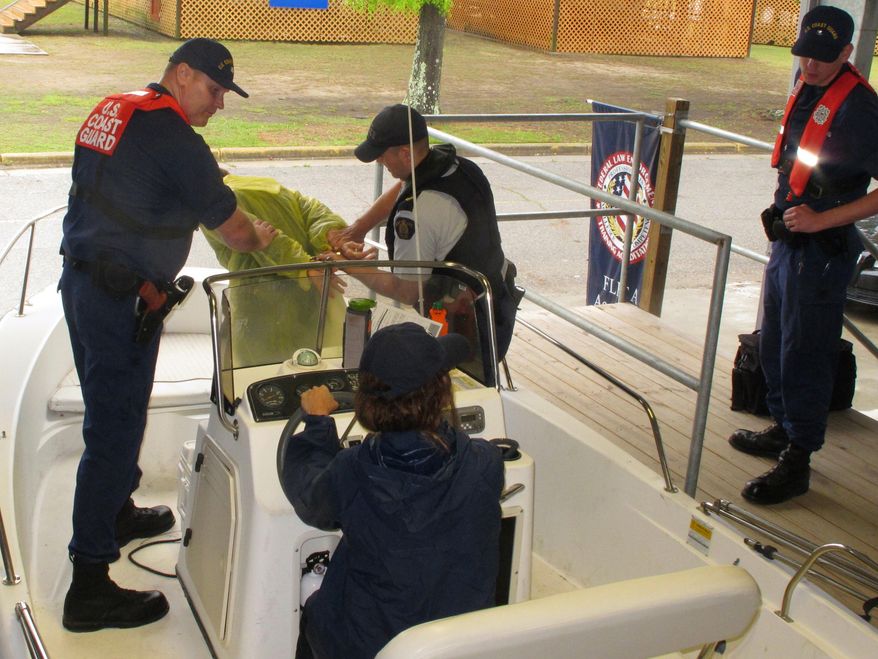Personnel from the U.S. Coast Guard and the Royal Canadian Mounted Police participate in a boat boarding exercise at the Federal Law Enforcement Training Center in Charleston, S.C., on Tuesday, April 15, 2014. The personnel are training for the Shiprider program, a joint effort in which law enforcement personnel from both agencies ride on the same boats to patrol the border between the United States and Canada. (AP Photo/Bruce Smith)