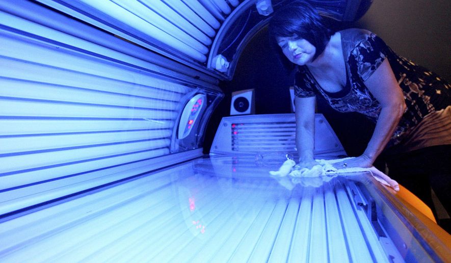 In this April 2, 2014 photo, Teresa Lynch, owner of Dynamic Tanning in DeKalb, Ill.,. wipes down a tanning bed. Lynch has noticed a slight decrease in tanners since a new state law prohibits those under the age of 18 to use tanning beds, but she says that many of her younger customers now come to spray tan. Lynch said she opposed the law and has always required parents to sign a consent form. Still, she&#39;s working with staff follow the new rules. (AP Photo/Daily Chronicle, Monica Maschak)  MANDATORY CREDIT