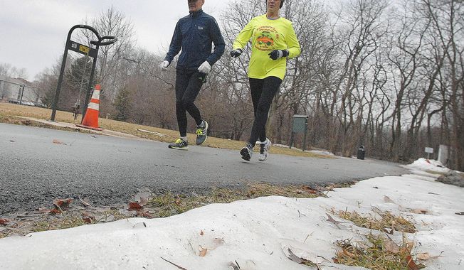 ADVANCE FOR USE SATURDAY, APRIL 19 AND THEREAFTER - In this March 19, 2014 photo, Merlin and Meg Anderson navigate Constitution Trail near the Connie Link Amphitheater in Normal, Ill. Icy trails and sidewalks can be hazardous for runners. (AP Photo/The Pantagraph, Davd Proeber)