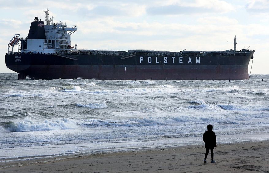 A person walks along the beach Wednesday, April 16, 2014, near where the 751-foot bulk carrier Ornak ran aground Tuesday night in the lower Chesapeake Bay near First Landing State Park, in Virginia Beach, Va. There were no reports of injuries, damage or pollution from the grounding, and the vessel was not blocking other water traffic, said Coast Guard spokesman Petty Officer First Class Brandyn Hill. (AP Photo/The Virginian-Pilot, Steve Earley) MAGS OUT