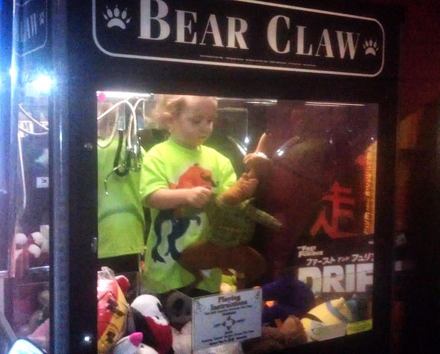 In this April 14, 2014 photo provided by Rachelle Hildreth, a 3-year-old boy plays with stuffed toys inside a claw crane game machine at a bowling alley in Lincoln, Neb. Police say a 24-year-old woman called 911 Monday afternoon because son was missing from her apartment. Authorities say the toddler was reunited, unharmed, with his mother after employees found him inside the coin-operated game. (AP Photo/Courtesy Rachell Hildreth)