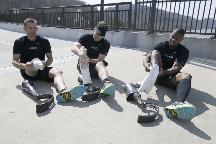 In this photo taken March 29, 2014, amputee marathon runners Jeff Glasbrenner, left, Chris Madison, center, and Andre Slay go through an exercise where they remove their running legs and adjust fittings in Little Rock, Ark. the runners must stop periodically in a race and try to loose as little time as possible. (AP Photo/Danny Johnston)
