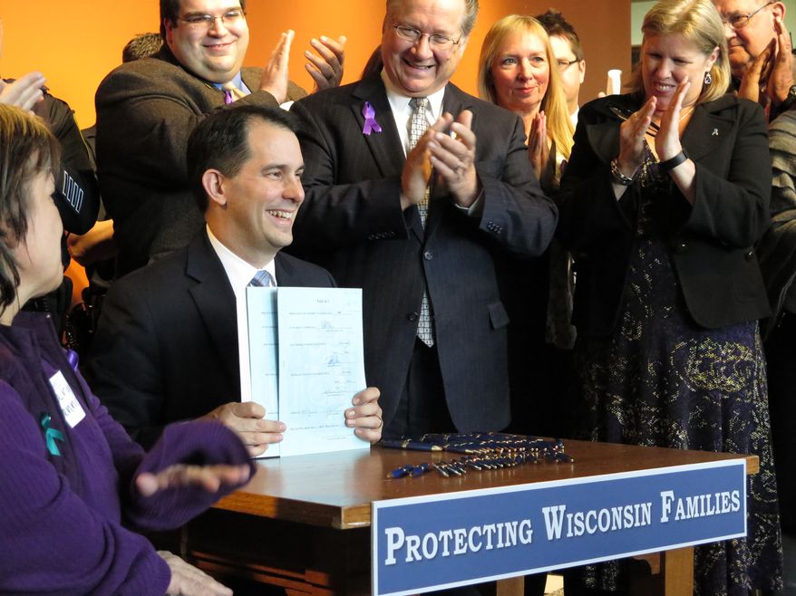 Wisconsin Gov. Scott Walker speaks to supporters of domestic-violence victims on Wednesday, April 16, 2014, in Milwaukee, just before signing three bills aimed at strengthening domestic-violence laws. The measures increase police responsibilities when investigating domestic disturbances and also establish a clear, accountable process for seizing an abuser's guns. (AP Photo/Dinesh Ramde)
