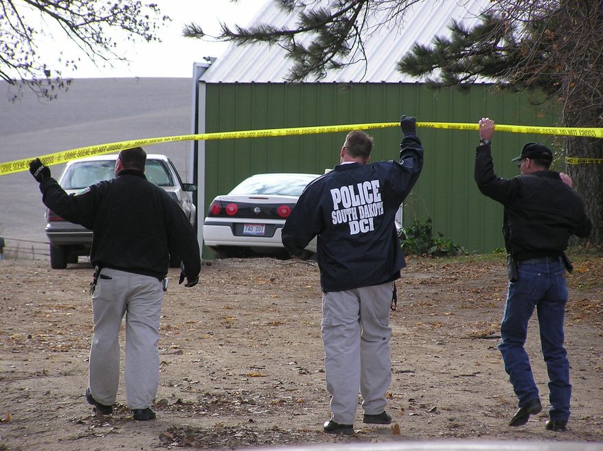 FILE - In this Nov. 16, 2004 file photo state and local investigators cross a police line at a farm near Nora, S.D., searching for evidence in the disappearance of Pamella Jackson and Cheryl Miller. The search yielded nothing and the girls disappearance baffled investigators for more than four decades. On April 15, 2014 authorities said the remains of the two 17-year-old South Dakota girls had been found in a car, upside-down in a creek near the party they were driving to celebrate the end of the school year with classmates in 1971. (AP Photo/Carson Walker, File)