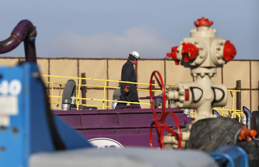In this March 25, 2014 photo, a worker watches over a hydraulic fracturing operation at an Encana Corp. gas well, near Mead, Colo. In the background is a tall canvas wall around the perimeter of the extraction site, which mitigates noise, light and dust coming from the operation during the drilling and completion phase, which generally takes a few weeks. (AP Photo/Brennan Linsley)