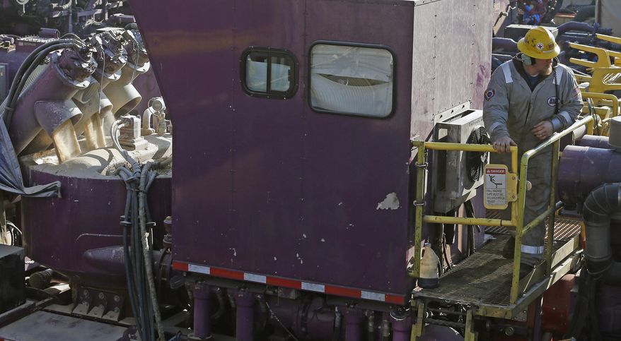In this March 25, 2014 photo, a worker climbs down a from a machine that mixes sand and water, left, before it is pumped underground during a hydraulic fracturing operation at an Encana Corp. well pad near Mead, Colo. Hydraulic fracturing, or "fracking,"is the practice of injecting water, sand and chemicals into source rock to crack it and create escape routes for oil and gas. (AP Photo/Brennan Linsley)