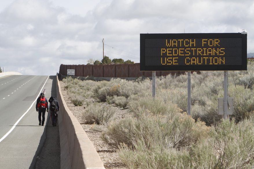Monica Pasquale, from Acoma Pueblo, hikes with her daughter Mari Chino, 12, on U.S. Highway 84/285 on their way to the Santuario de Chimayo on Thursday, April 17, 2014. The shrine, a National Historic Landmark, is famous for the story of its founding and as a contemporary pilgrimage site. Pasquale has been walking from Sky City Casino since Sunday and estimates she will make it to Chimayo on Friday evening.  (AP Photo/The New Mexican, Luis Sanchez Saturno)