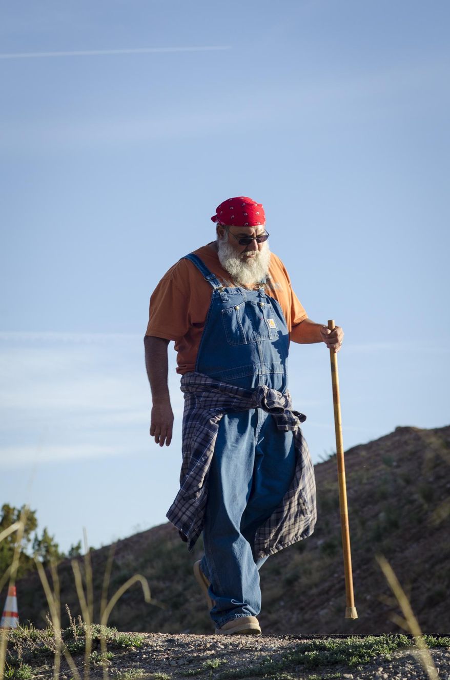 Dennis Martinez of Albuqurque, New Mexico makes his way down the last stretch of highway before entering El Santuario de Chimayo, a journey that took him more than three days on foot, Thursday, April 17, 2014. As many as 40,000 pilgrims journey to El Santuario each year during the Easter weekend. (AP Photo/Jeremy Wade Shockley)