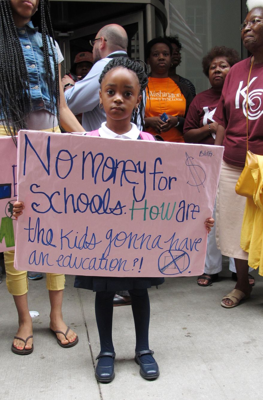 FILE - In this Aug. 28, 2013 file photo, Lariyah Beasley, a 4-year-old preschool student from Chicago, holds a sign during a rally outside the Chicago Board of Education headquarters in Chicago. Dozens of protesters, including Lariyah's mother and other parents, students and activists, decried the lack of funding for the city's public school students, especially for African American students. Most of Illinois’ 860 school districts would see severe cuts in funding if the state’s temporary tax increase is rolled back as scheduled, according to a document circulated this week as part of Illinois Democrats’ campaign to preserve the tax hike and push to update the state’s school funding formula. The document cites what would be a total of $450 million in general state aid cuts to schools. (AP Photo/Martha Irvine,File)