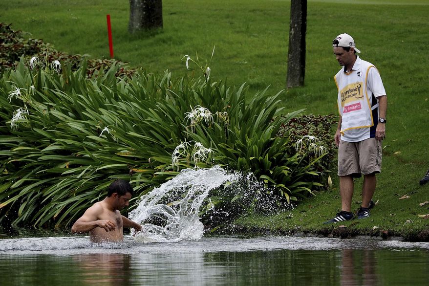 Pablo Larrazabal, left, of Spain, jumps into a lake after being attacked by a swarm of hornets during the second round of the Malaysian Open golf tournament at Kuala Lumpur Golf and Country Club in Kuala Lumpur, Malaysia, Friday, April 18, 2014. (AP Photo/Joshua Paul)