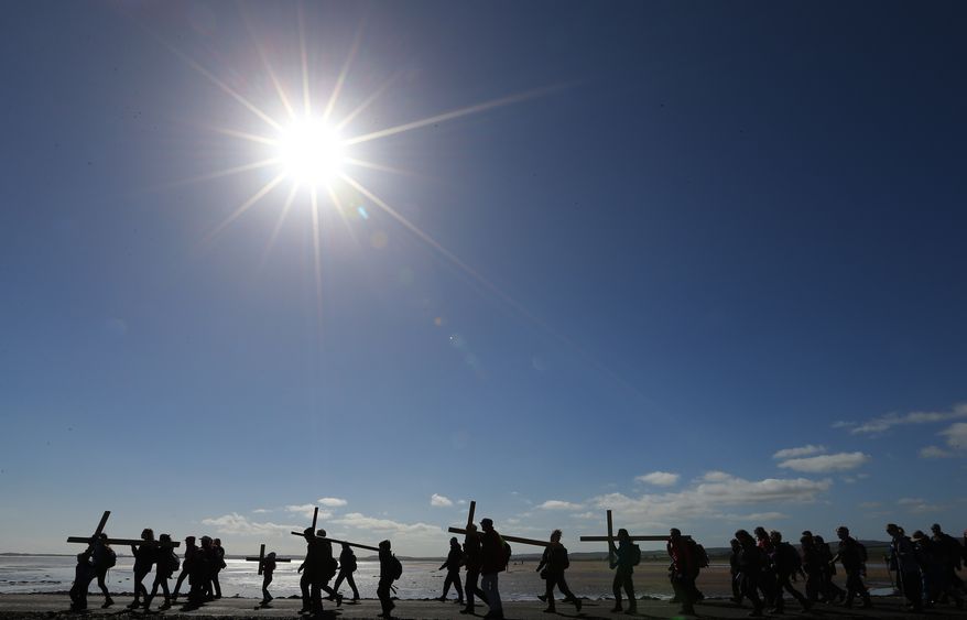 Pilgrims walk with crosses as the Northern Cross pilgrimage makes its final leg of the journey to Holy Island, Berwick Upon Tweed, England, Friday, April 18, 2014. For more than 30 years, groups of pilgrims celebrate Easter by crossing the tidal causeway during the annual Christian cross carrying pilgrimage to Holy Island , the pilgrims walk around 100 miles through Northumberland and the Scottish Borders during Holy Week. (AP Photo/Scott Heppell).