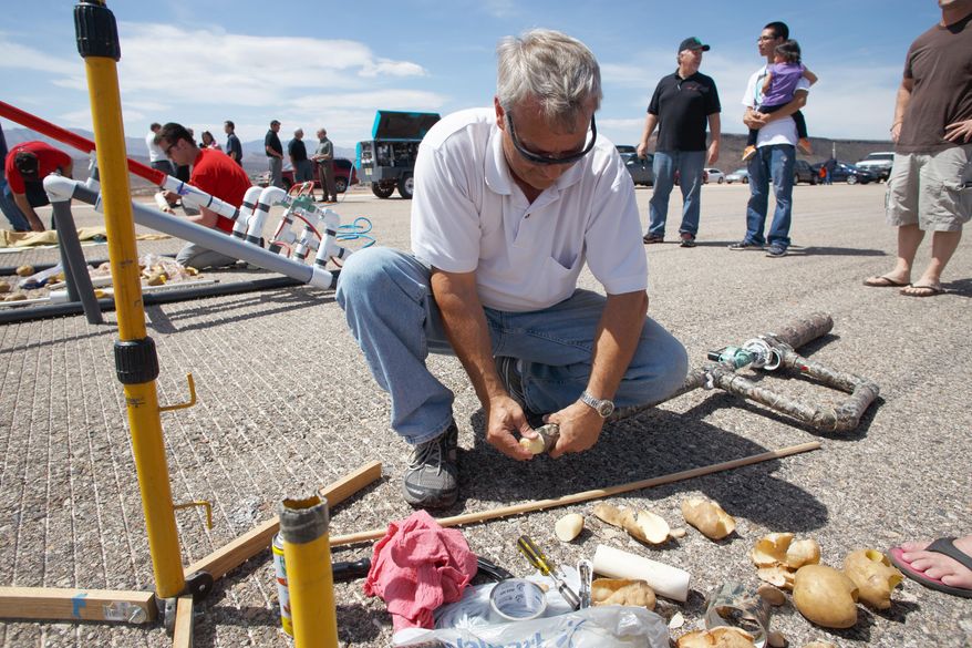 In a Wednesday, April 16, 2014 photo, Tom Johnson, a student in an Industrial and Facilities Maintenance class at Dixie Applied Technology College (DXATC), loads a potato cannon he built for the class on the old St. George Airport runway.There was a competition to see who could make the vegetables fly the farthest at the south end of the old runway. Students majoring in industrial facilities maintenance are studying what's called fluid power, which includes hydraulic, pneumatic, pump and valve system science. (AP Photo/The Spectrum, Jud Burkett)