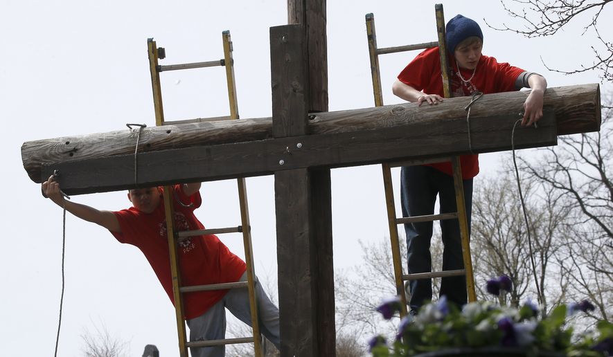 Volunteers tie the wooden cross that was carried through the streets of Etna, Pa., a Pittsburgh suburb, to the larger cross in the cemetery where their annual &quot;Drama of The Cross,&quot; service was done on Good Friday, Friday, April 18, 2014. (AP Photo/Keith Srakocic) ** FILE **