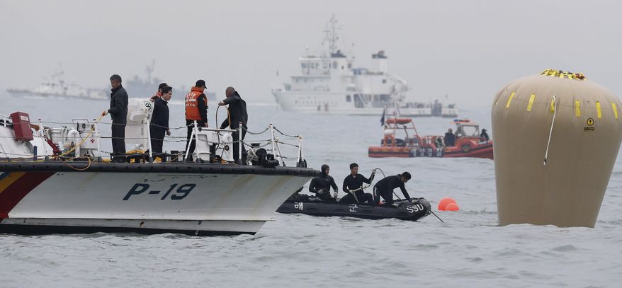 South Korean navy personnel install a buoy to mark the sunken passenger ship Sewol in the water off the southern coast near Jindo, South Korea, Friday, April 18, 2014. Rescuers scrambled to find hundreds of ferry passengers still missing Friday and feared dead, as fresh questions emerged about whether quicker action by the captain of the doomed ship could have saved lives. (AP Photo/Yonhap) KOREA OUT