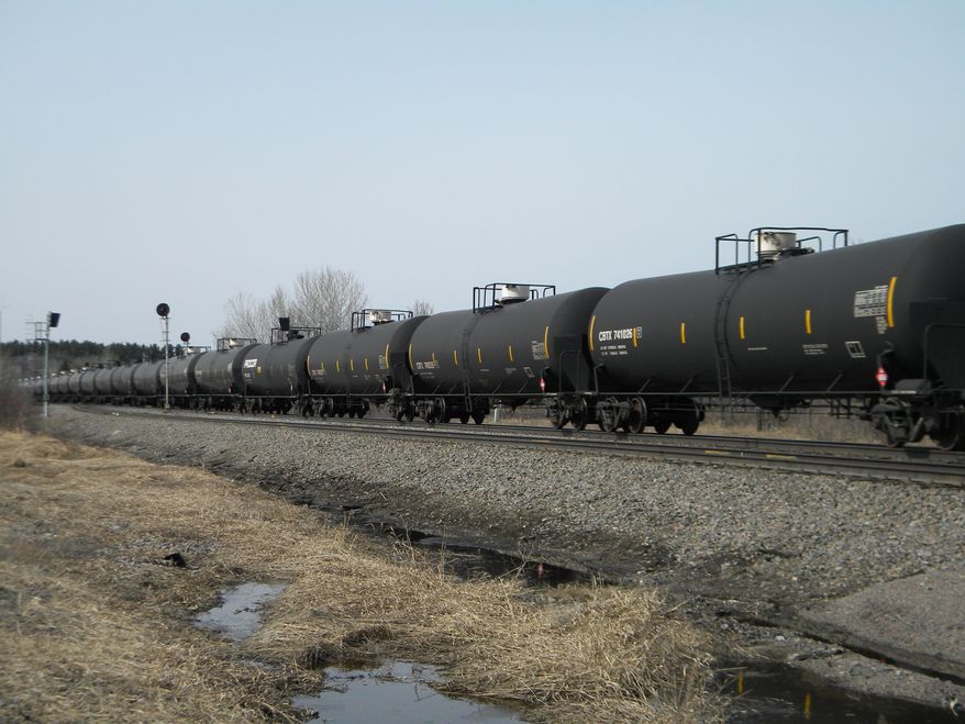In this April 15, 2014 photo, an oil-tank train operated by Burlington Northern Santa Fe Corp., based in Fort Worth, Texas, cruises east alongside U.S. 10, a few miles outside of Staples, Minn. Multiple BNSF oil-tank trains travel through Staples every day, pulling about 110 tanks, sometimes more, of highly volatile crude from the Bakken shale fields in North Dakota to refineries east and south of Minnesota. (AP Photo/Mike Cronin)