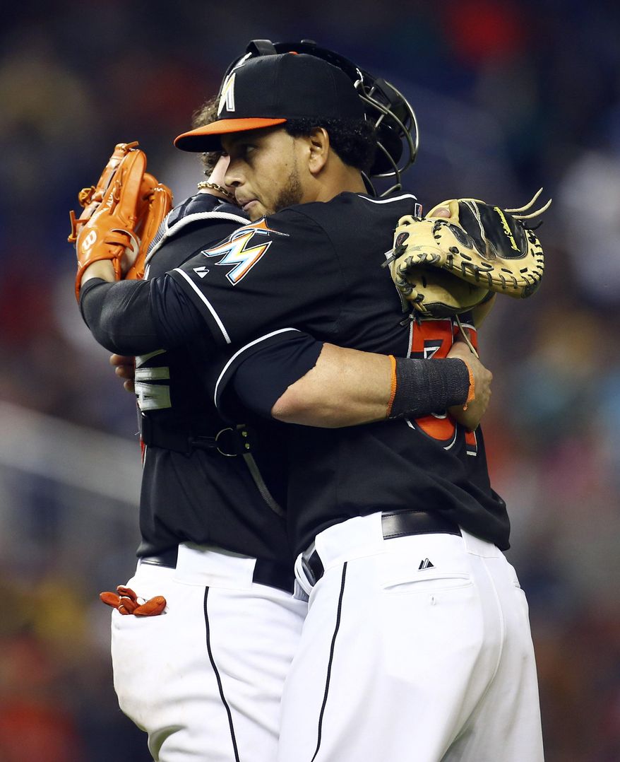Miami Marlins starting pitcher Henderson Alvarez, right, hugs catcher Jarrod Saltalmacchia after a baseball game against the Seattle Mariners in Miami, Saturday, April 19, 2014. The Marlins won 7-0. (AP Photo/J Pat Carter)
