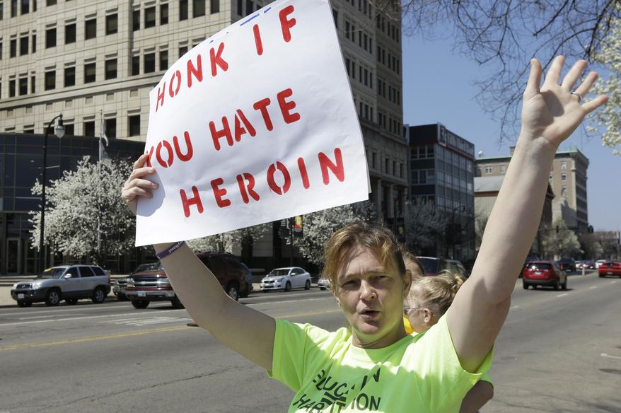 In this April 19, 2014, photo, Candy Murray Abbott waves at passing motorists during an anti-heroin rally held by Heroin Control in Hamilton, Ohio. (AP Photo/Al Behrman)