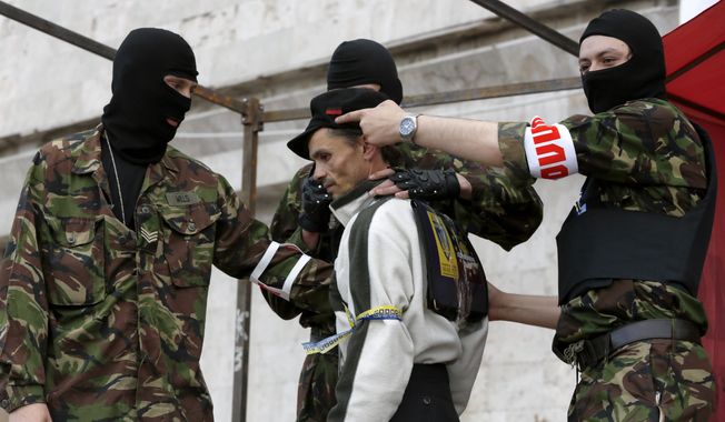 A shootout at the Russia-Ukraine border between an unidentified masked man and pro-Russian activists broke a United Nations brokered truce and left at least three dead on Easter Sunday, prompting a small memorial at the scene of the skirmish. (Associated Press Photographs)