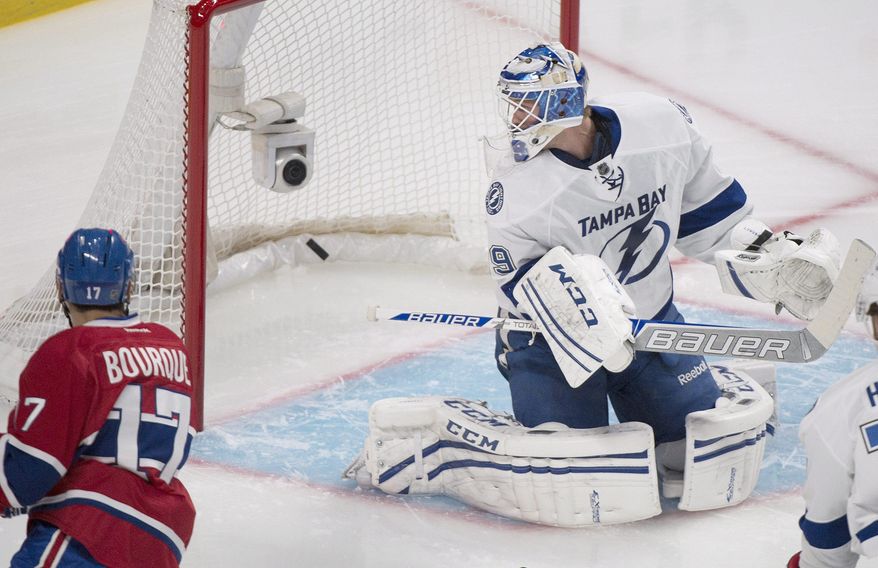 Montreal Canadiens' Rene Bourque, left, scores against Tampa Bay Lightning's goalie Anders Lindback during first period of the first round NHL Stanley Cup playoff game in Montreal, Sunday, April 20, 2014. (AP Photo/The Canadian Press, Graham Hughes)