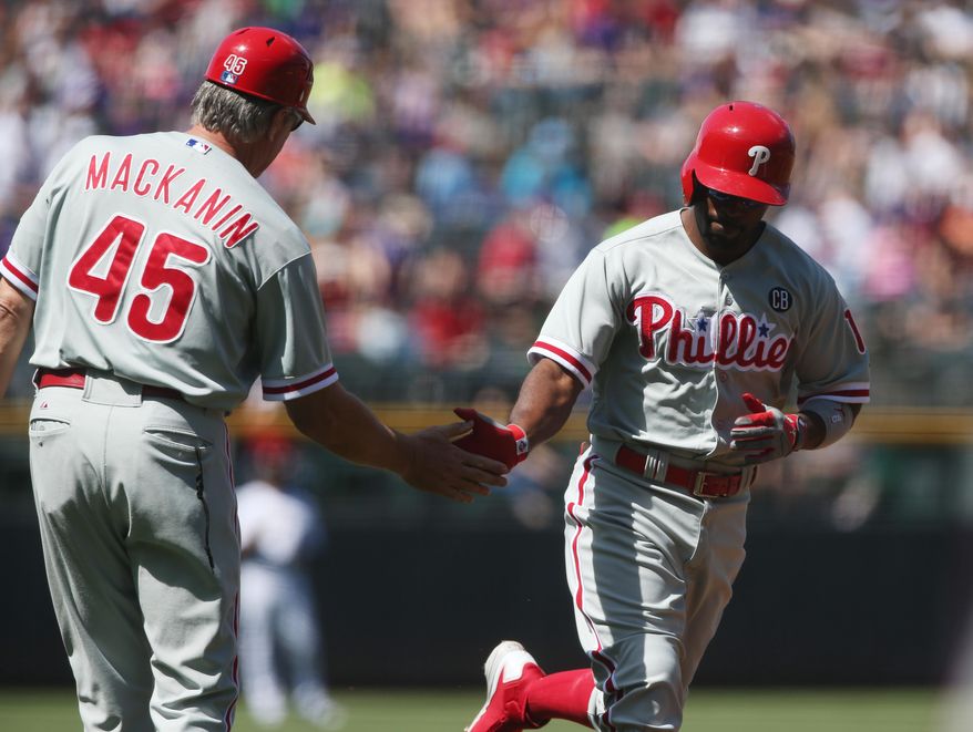 Philadelphia Phillies third base coach Pete Mackanin, left, congratulates Jimmy Rollins who circles the bases after hitting a solo home run against the Colorado Rockies in the first inning of a baseball game in Denver, Sunday, April 20, 2014. (AP Photo/David Zalubowski)