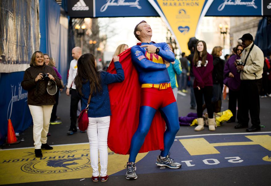 Trent Morrow of Sydney, Australia, also know as “Marathon Man” laughs as Andrea Olivo of Venezuela tugs on his cape as she has her photo made ahead of Monday's 118th Boston Marathon, Sunday, April 20, 2014, in Boston. Morrow says Monday's marathon will be his 200th run since Jan. 1, 2013. (AP Photo/Matt Rourke)