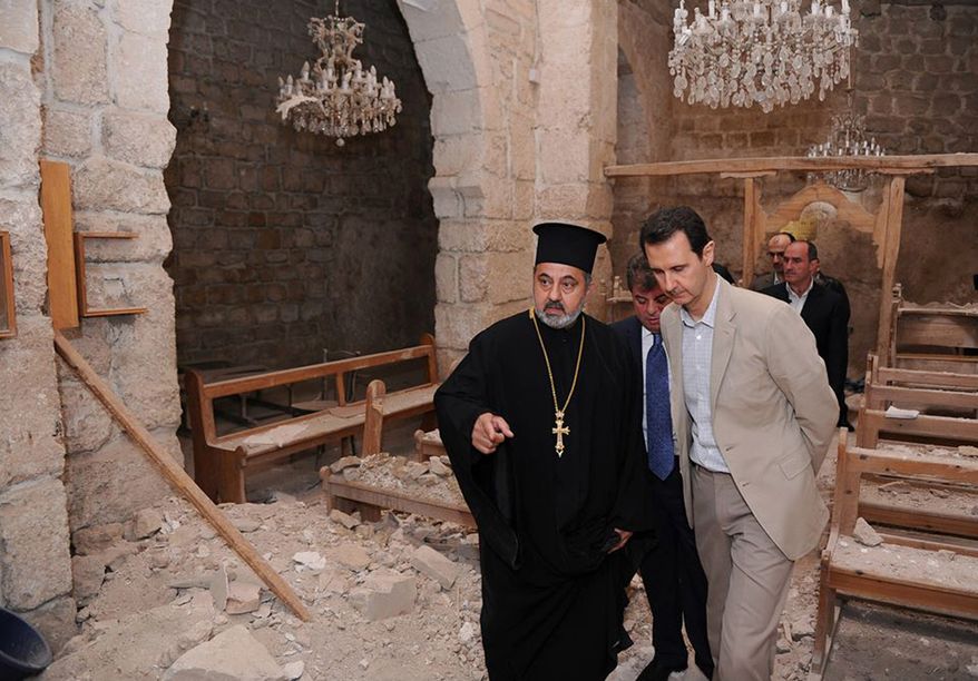 In this photo taken on Sunday, April 20, 2014, and released on the official Facebook page of the Syrian Presidency, Syrian President Bashar Assad, right, checks a damaged church during his visit to the Christian village of Maaloula, near Damascus, Syria. Assad visited on Sunday a historic Christian village his forces recently captured from rebels, state media said, as the country's Greek Orthodox Patriarch vowed that Christians in the war-ravaged country "will not submit and yield" to extremists. The rebels, including fighters from the al-Qaida-affiliated Nusra Front, took Maaloula several times late last year. (AP Photo/Syrian Presidency via Facebook)