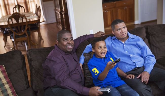 Shelton Stroman, left, and partner Christopher Inniss, right, watch television at home with their son Jonathan, 9, Thursday, April 17, 2014, in Snellville, Ga. A gay rights group on Tuesday, April 22, 2014, filed a federal lawsuit in Atlanta challenging the state of Georgia’s constitutional ban on same-sex marriages. Georgia voters in 2004 overwhelmingly approved a constitutional ban on gay marriage in 2004. The ban was challenged in courts by gay rights groups who challenged the wording of the ballot question, but the state Supreme Court ultimately ruled the vote was valid in 2006. (AP Photo/David Goldman)