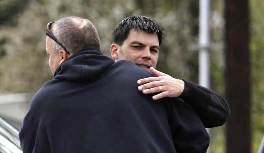 Snohomish County District 21 Fire Chief Travis Hots, right, gets a hug from former classmate Matt Ingison Tuesday, April 22, 2014, at the fire station in Oso, Wash. President Barack Obama plans a brief visit to the area about an hour northeast of Seattle to survey damage from a recent mudslide nearby that killed more than three dozen people. The deadly March 22 mudslide killed at least 41 people and buried dozens of homes. (AP Photo/Elaine Thompson)
