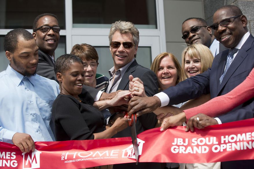 Jon Bon Jovi, center, takes part in a ribbon cutting ceremony during the grand opening of the JBJ Soul Homes, Tuesday, April 22, 2014, in Philadelphia. On Tuesday, Bon Jovi attended the grand opening of a low-income housing development that bears his initials. The 55-unit JBJ Soul Homes will be occupied by low-income tenants and the formerly homeless. Bon Jovi's Soul Foundation and the Middleton Partnership provided the lead gift for the $16.6 million complex in the Francisville neighborhood. The project also received public funds. (AP Photo/Matt Rourke)