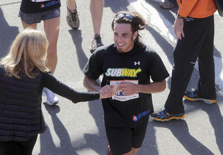 FILE - In this Nov. 6, 2011 file photo, Apolo Ohno crosses the finish line at the New York City Marathon in New York. The most decorated U.S. Winter Olympian in history is taking on a new athletic challenge: an Ironman triathlon. Ohno plans to compete at the world championship in Kailua-Kona, Hawaii, in October _ swim 2.4 miles, bike 112 miles, then run a marathon. (AP Photo/Seth Wenig, File)