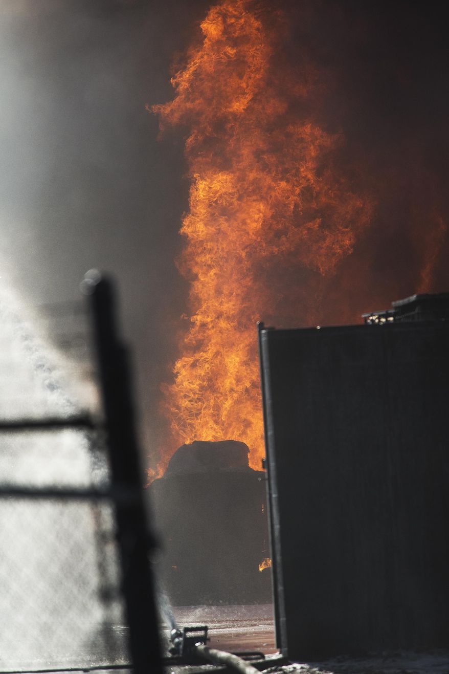 Flames shoot up from a fire that broke out an oil tanker business in an industrial area Tuesday, April 22, 2014, in Phoenix, Ariz. About 20 engines and ladder trucks were dispatched. and two men were critically injured. (AP Photo/The Arizona Republic, Tom Tingle) MARICOPA COUNTY OUT; MAGS OUT; NO SALES