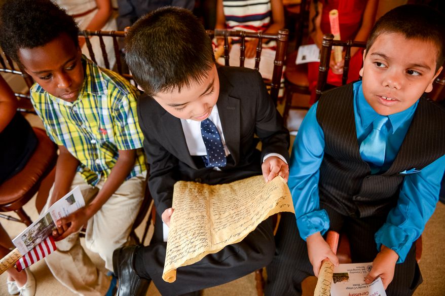 Kyle Roup, 9, from South Korea, center, read his copy of the Emancipation Proclamation before he and other children take their Naturalization Oath of Allegiance at Lincoln's Cottage, Washington, D.C., Tuesday, April 22, 2014. Twenty area children representing 15 countries receive their Certificates of Citizenship during a special ceremony at President Lincoln's Cottage, where it is believed President Abraham Lincoln drafted the Emancipation Proclamation. (Andrew Harnik/The Washington Times)
