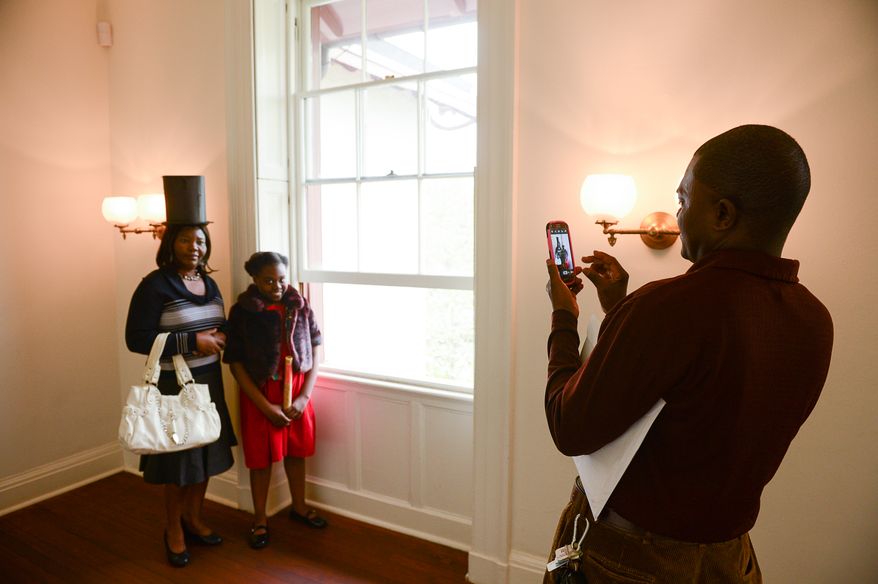 Kosta Gao of Washington, D.C., right, takes a photo of his wife Mary Dzrara, left, and their daughter Claudia Gao, 11, right, from Syria after she is sworn in as a U.S. Citizen at Lincoln's Cottage, Washington, D.C., Tuesday, April 22, 2014. Twenty area children representing 15 countries receive their Certificates of Citizenship during a special ceremony at President Lincoln's Cottage, where it is believed President Abraham Lincoln drafted the Emancipation Proclamation. (Andrew Harnik/The Washington Times)