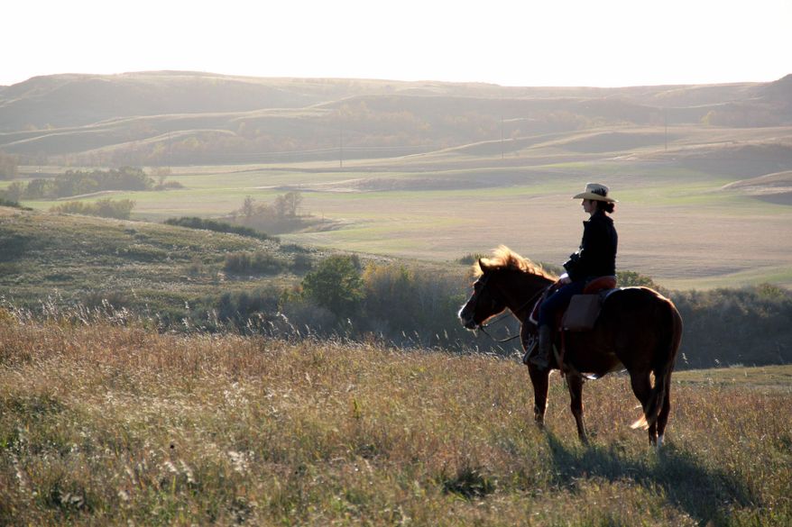 ADVANCE FOR USE TUESDAY, APRIL 29, 2014 AND THEREAFTER - This October 2013 photo provided by Jessie Veeder shows her riding a horse to chase cattle with her sister, husband and father, not pictured, on the Veeder Ranch in Watford City, N.D. Veeder's husband works in the oil fields. She blogs about her love of open space and her pride at living in the place her great-grandfather called home. But she says, "You can't have it both ways _ you can't have this real booming industry, all this economic growth and all this prosperity without having some repercussions." (AP Photo/Jessie Veeder)