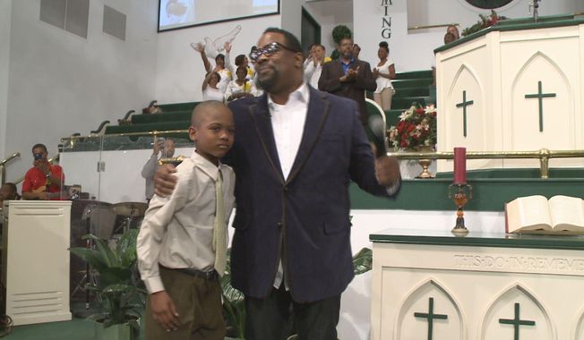 In an April 10, 2014, image provided by WXIA-TV, 9-year-old Willie Myrick is embraced by Grammy Award-winning gospel singer Hezekiah Walker in front of the congregation at Mt. Carmel Baptist Church in Atlanta.  Police say Myrick was abducted from his driveway but was released after singing the gospel song &amp;quot;Every Praise&amp;quot; until the abductor released him.  (AP Photo/WXIA-TV)