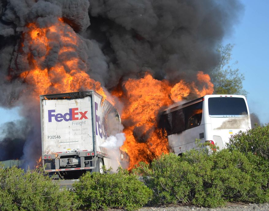 FILE - In this Thursday, April, 10, 2014, file photo, massive flames engulf a tractor-trailer and a tour bus just after they collide on Interstate 5, near Orland, Calif. The mother of a 17-year-old honors student who was among 10 people killed in the fiery Northern California bus crash sued FedEx on Tuesday, April 22, 2014, alleging that its trucks have a history of catching fire. (AP Photo/Jeremy Lockett, File)