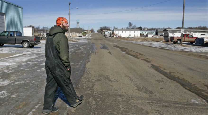 ADVANCE FOR USE TUESDAY, APRIL 29, 2014 AND THEREAFTER - In this Thursday, Feb. 27, 2014 photo, Daniel Ibsen, a gas station clerk, walks to his car on his lunch break in Grenora, N.D. Ibsen, 31, grew up in Grenora and says this latest oil boom is bringing bigger changes than ever to town. Not so long ago, he says the high school's graduating class was down to two people. But he says the school has many more students because of the oil boom. The town also has recently built modular homes and a new oil storage facility across the highway. (AP Photo/Martha Irvine)