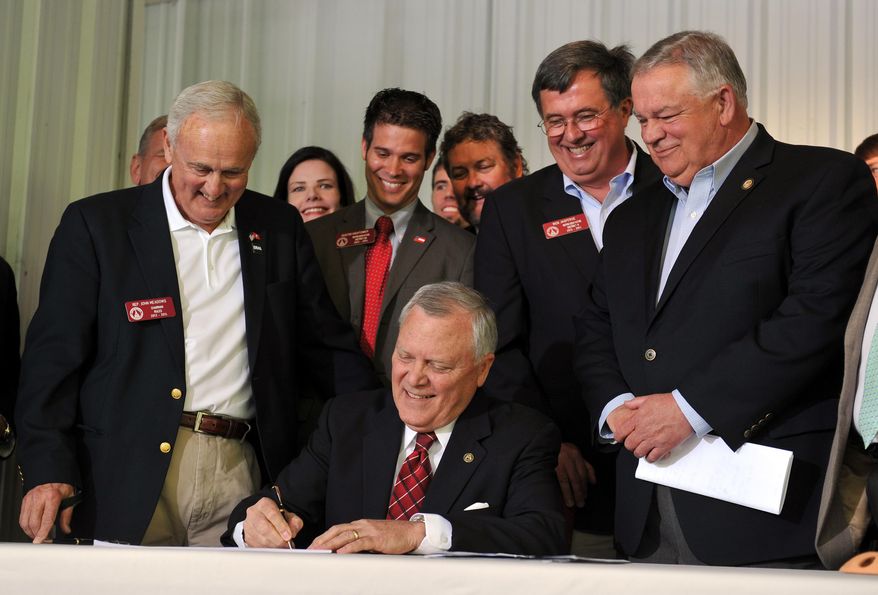 Surrounded by bill supporters, Georgia Gov. Nathan Deal signs House Bill 60 into law during a signing event Wednesday, April 23, 2013, in Ellijay, Ga. The bill makes several changes to the state's gun law. It allows those with a license to carry to bring a gun into a bar without restriction and into some government buildings that don't have certain security measures. It also allows religious leaders to decide whether it's OK for a person with a carry license to bring a gun into their place of worship. (AP Photo/Atlanta Journal-Constitution, Brant Sanderlin) MARIETTA DAILY OUT; GWINNETT DAILY POST OUT; LOCAL TV OUT; WXIA-TV OUT; WGCL-TV OUT