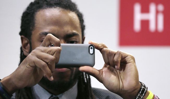Seattle Seahawks cornerback Richard Sherman takes a photograph of the audience during a panel discussion at Harvard University in Cambridge, Mass., Wednesday, April 23, 2014. Sherman told Harvard students that he refuses to back down from his rant after the NFC championship game because he wants to “educate the uneducated.” (AP Photo/Charles Krupa)