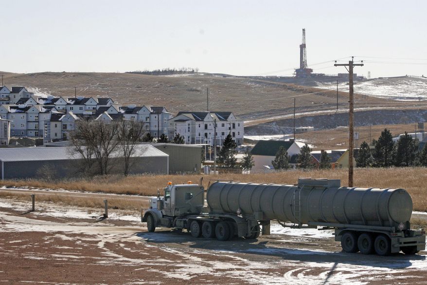 ADVANCE FOR USE TUESDAY, APRIL 29, 2014 AND THEREAFTER - In this Wednesday, Feb. 26, 2014 photo, an oil truck sits in a dirt lot near a new housing development in Watford City, N.D. The housing development is part of the towns growth explosion from the Baaken oil boom. For years, the town's population hovered around 1,500. Now its at about 7,000 - a number that's expected to more than double in years to come. (AP Photo/Martha Irvine)