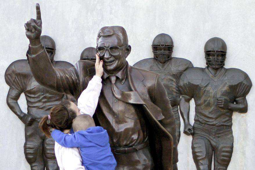 FILE - In this Oct. 8, 2010 file photo, Ashley Buchan holds her 4-year-old nephew Caleb Anthony, as she reaches to touch the face of the statue of former Penn State football coach Joe Paterno outside Beaver Stadium in State College, Pa. In 2012, the school removed this Paterno statue after a university-commissioned report accused the late coach and three other administrators of concealing sex abuse claims against retired assistant coach Jerry Sandusky. Fans of the late coach are commissioning a new statue to be placed across from the school at a local restaurant. (AP Photo/Keith Srakocic,File)