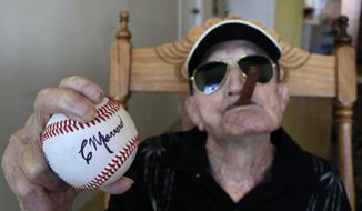 **FILE** In this April 23, 2013 photo, Cuba&#39;s former pitcher Conrado Marrero, the world&#39;s oldest living former major league baseball player, holds up a baseball with his signature at his home, two days before is 102nd birthday, as he holds an unlit cigar in his mouth in Havana, Cuba. (AP Photo/Franklin Reyes)