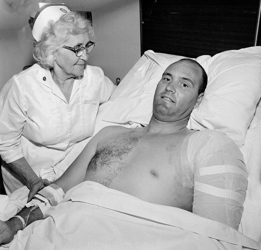 FILE - In this Aug. 3, 1966, file photo, Robert Heard, Associated Press staffer in Austin, Texas, is attended by his nurse, Annie Worley, at Brackenridge Hospital, where he is recovering from gunshot wounds suffered while he was covering a shooting spree at the University of Texas tower, in Austin. Heard, who reported on Texas state government, politics and sports for The Associated Press and a groundbreaking series on race and integration of Longhorns football, has died. He was 84. Heard died April 15, 2014, from complications after surgery to repair a broken hip, said widow Betsy Heard. (AP Photo/DO, File)