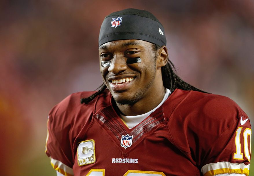 FILE - In this Nov. 25, 2013 file photo, Washington Redskins quarterback Robert Griffin III smiles as he walks along the sidelines before an NFL football game against the San Francisco 49ers in Landover, Md. Griffin III will drive the pace car before Saturday night's, April 26, 2014 NASCAR race at Richmond. Richmond International Raceway made the announcement Wednesday, April 23, 2014. (AP Photo/Evan Vucci, File)