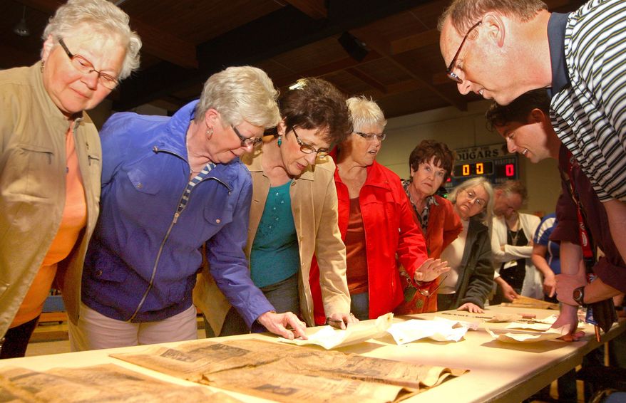In this photo taken on Wednesday, April 23, 2014, Aquin High School class of 1965 graduates, from left, Inez Merges, Jan Supple, Marie Steinlage, Corinne McQuillen, and Pam Gehl look at items found within a time capsule from 1961 at Cascade High School in Cascade, Iowa, that was found by construction crews. The capsule was opened during a school assembly on Wednesday. (AP Photo/The Telegraph Herald, Nicole Kohl) MAGS OUT. TV OUT