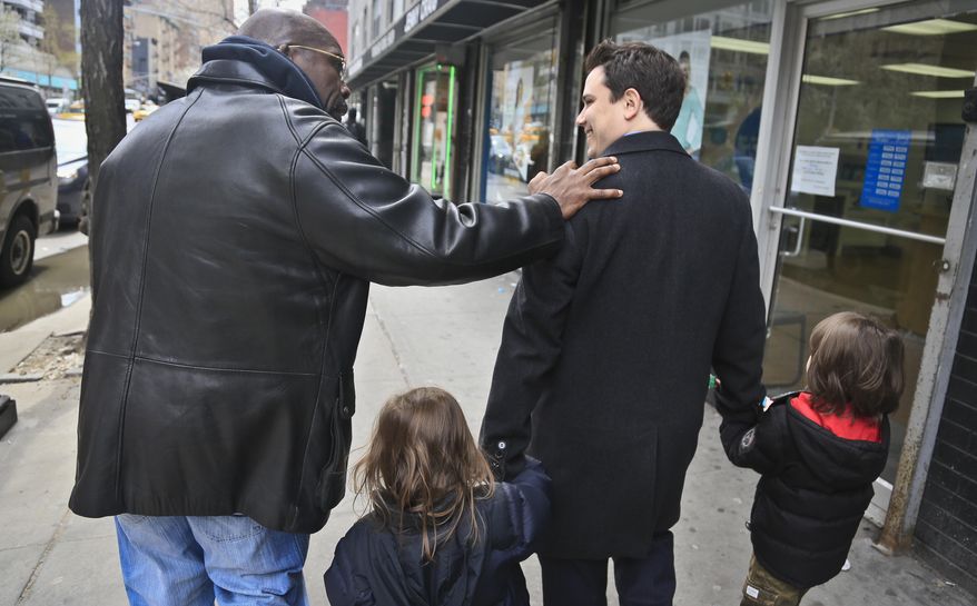 Attorney Taylor Koss, second from right, holds hands with his children Max, 6, far right, and Sam, 4, as he escorts his client Jonathan Fleming, far left, to open a bank account and get his first bankcard, on Friday April 18, 2014 in New York. Fleming was exonerated of murder after almost 25 years behind bars. The weeks since his release have been a mix of emotional highs and practical frustrations. “Coming back, you know, it’s been hard. ... It’s a lot to have to catch up on." (AP Photo/Bebeto Matthews)