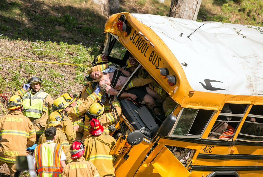 Firefighters extricate the driver from the front of a school bus that crashed, Thursday, April 24, 2014, in Anaheim, Calif. Three of the injured, the driver and two of the children, were taken to hospitals in critical condition after the crash, Anaheim police Lt. Bob Dunn said. The other nine students had minor injuries, and most of them were released to their parents. Police say no other vehicles were involved in the crash and there is no immediate word on the cause. (AP Photo/Kevin Warn)